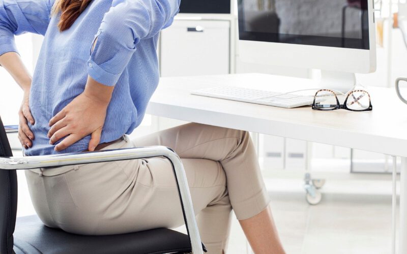 Kobieta z bólem pleców siedzący przy biurku