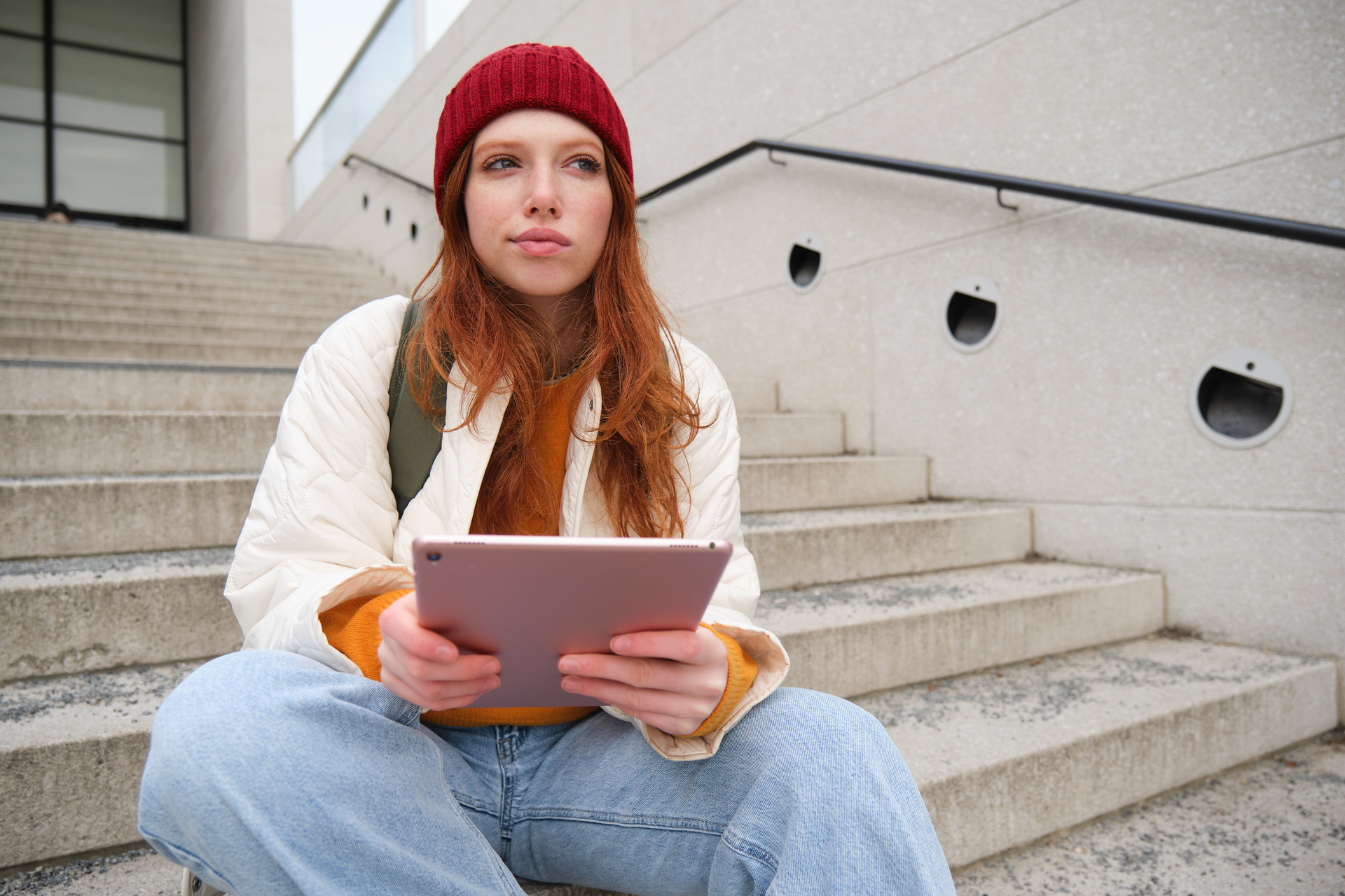 Studentka SGH z tabletem siedząca na schodach przed uczelnią